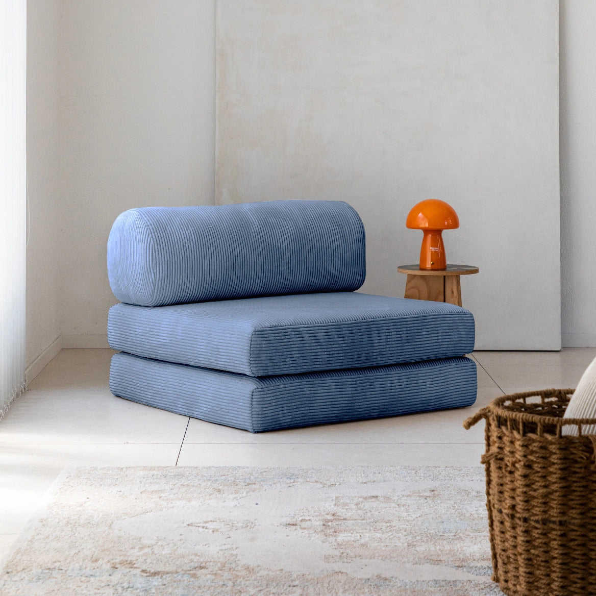 Blue floor cushions stacked on a light wooden floor with a white wall in the background.